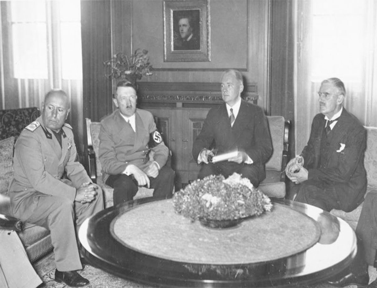 Benito Mussolini, Adolf Hitler, Édouard Daladier y Neville Chamberlain sentados alrededor de una mesa circular durante las negociaciones de Múnich.