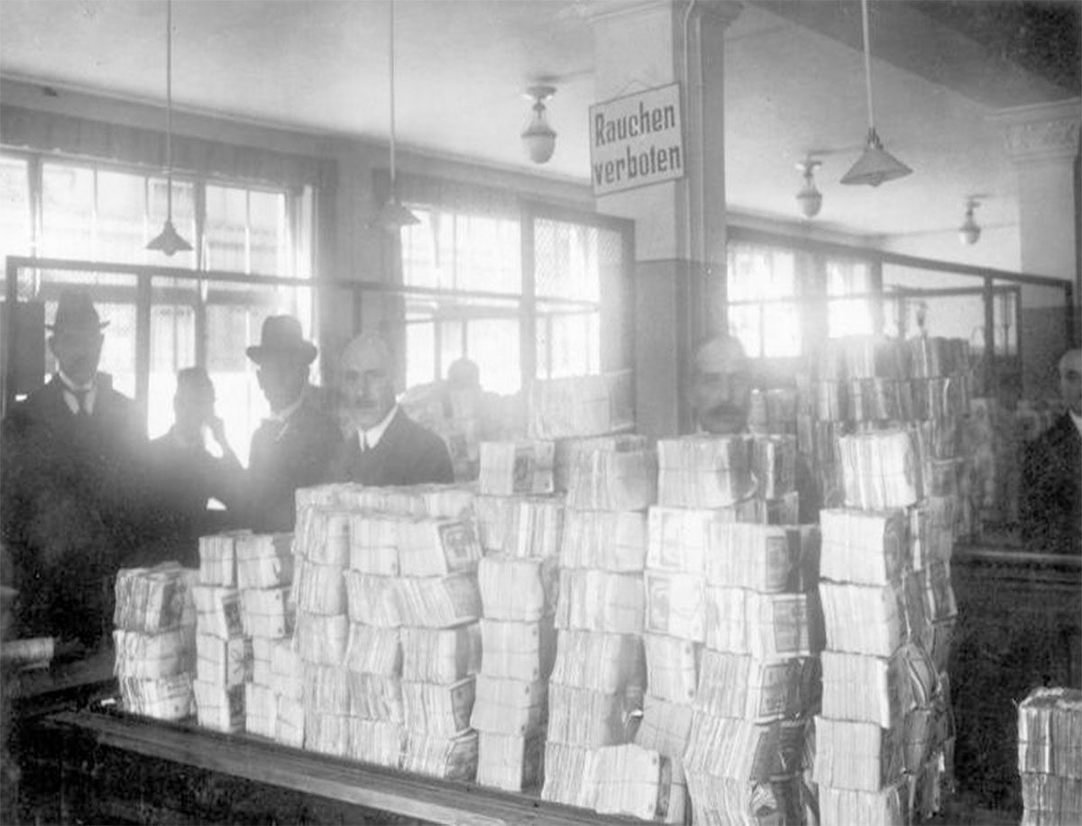 Empleados bancarios rodeados de enormes pilas de billetes de marcos alemanes durante la hiperinflación.