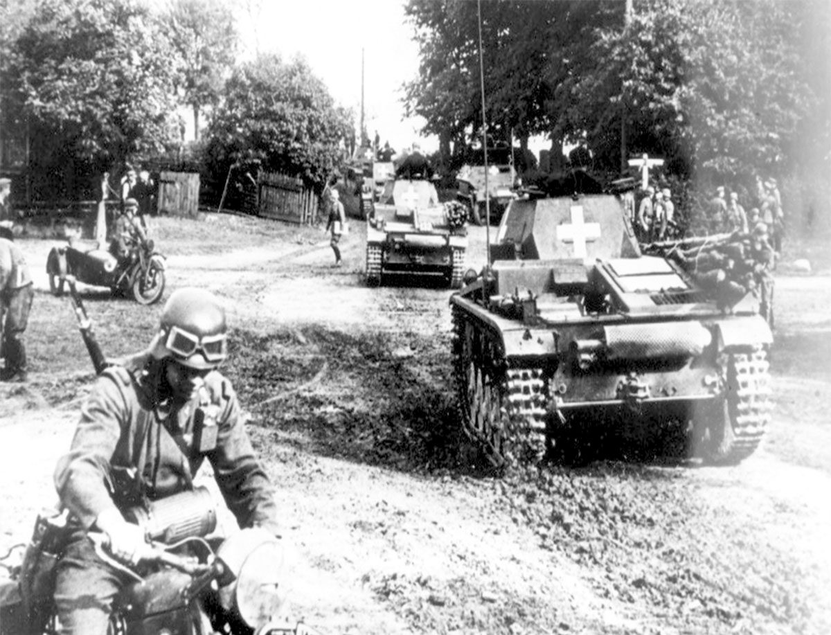 Tanques ligeros alemanes Panzer II y una motocicleta avanzando por un camino de tierra en Polonia.