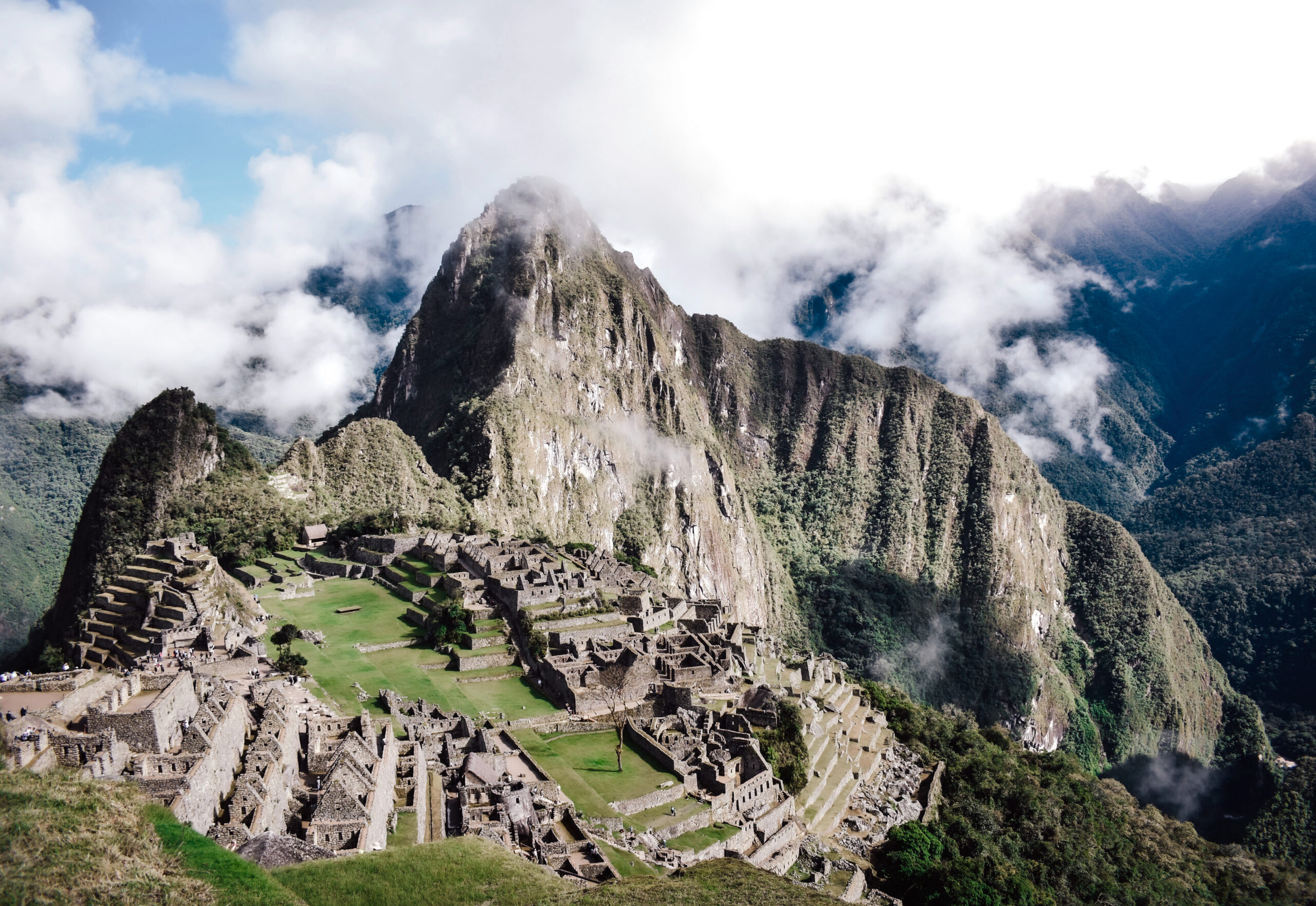 Vista panorámica de las ruinas de piedra de la ciudadela de Machu Picchu rodeada de terrazas verdes y montañas envueltas en nubes.