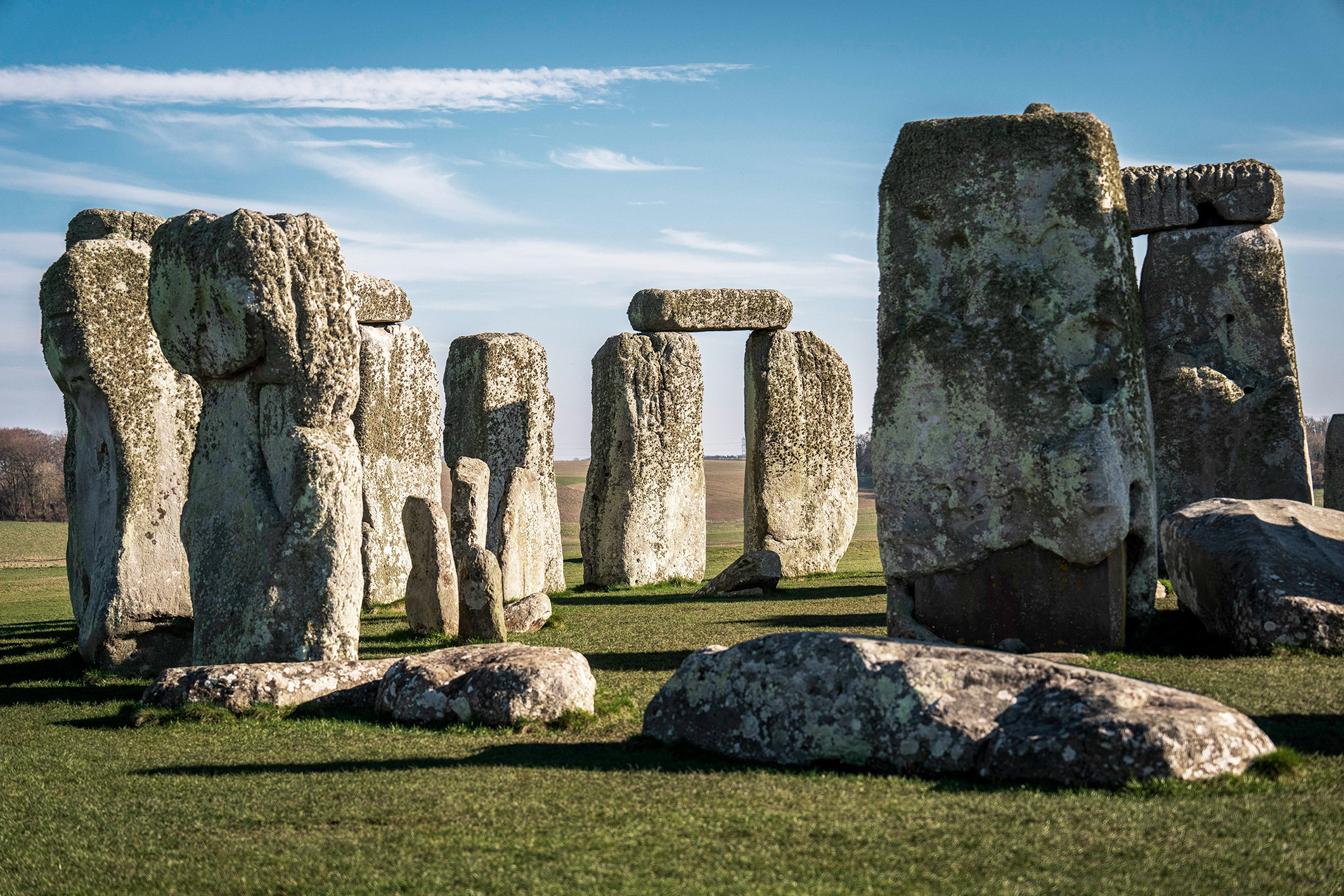 Vista en primer plano de los bloques de piedra sarsen cubierta de liquen en Stonehenge bajo un cielo despejado.